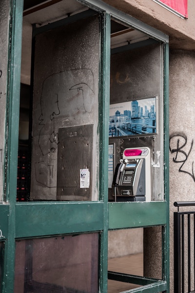 Picture of a phone booth wiuth grafitti on it.