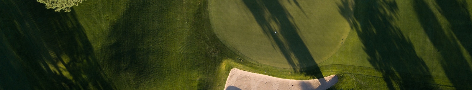 Aerial photo of a golf green with flag pin.