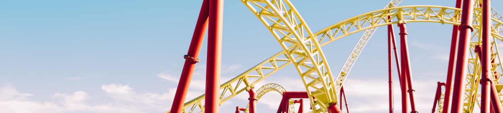 Roller coaster at a theme park with yellow tracks and red supports.