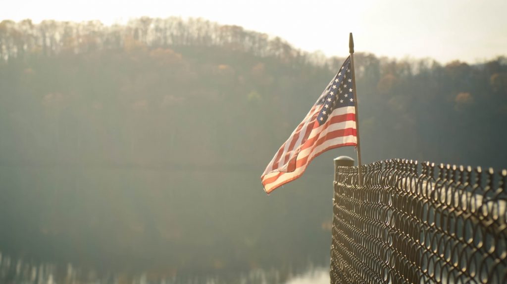 American flag on a fence with forest and snow in background